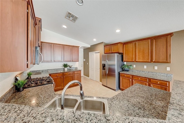 kitchen with light stone counters, appliances with stainless steel finishes, a sink, and visible vents