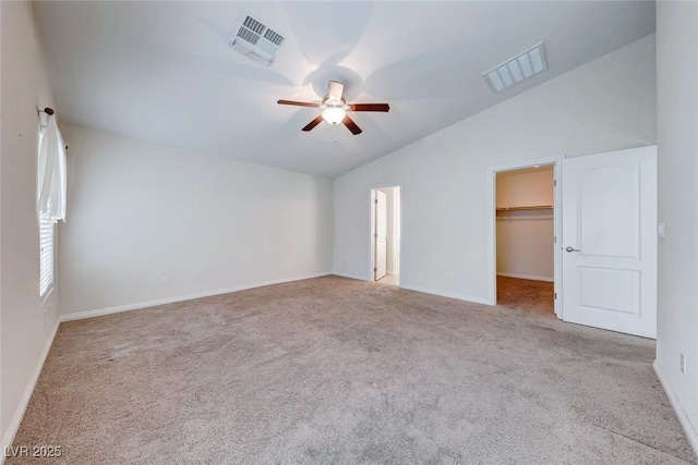 unfurnished bedroom featuring lofted ceiling, carpet, visible vents, and a walk in closet