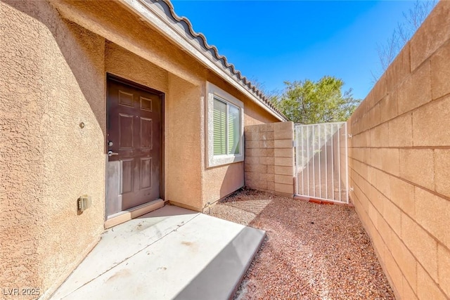 entrance to property with a tile roof, a gate, fence, and stucco siding