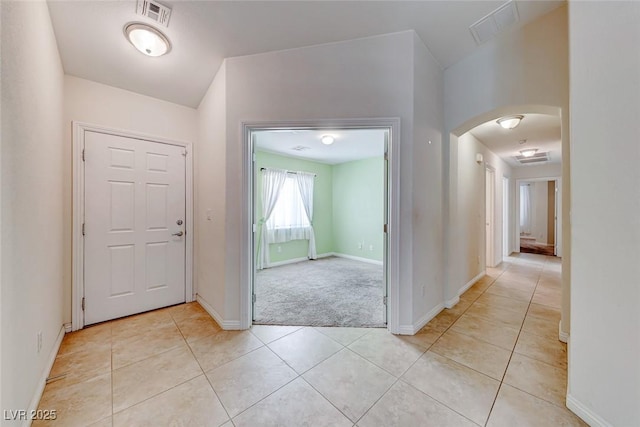 entryway featuring baseboards, visible vents, arched walkways, and light tile patterned flooring