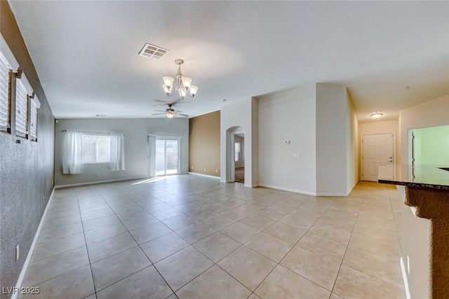 spare room with light tile patterned floors, visible vents, arched walkways, lofted ceiling, and ceiling fan with notable chandelier