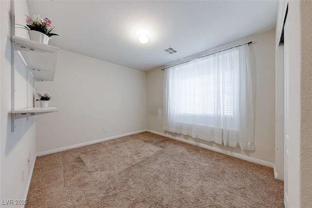 carpeted spare room with visible vents and baseboards