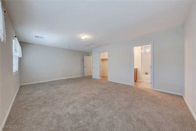 unfurnished bedroom featuring light carpet, visible vents, baseboards, a spacious closet, and attic access