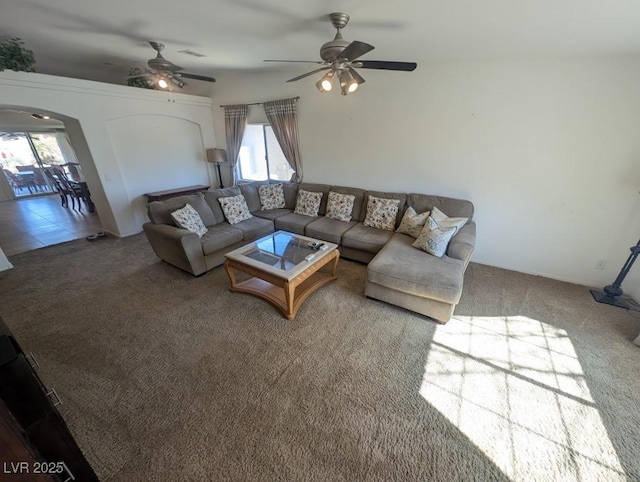 carpeted living room featuring visible vents, arched walkways, and ceiling fan