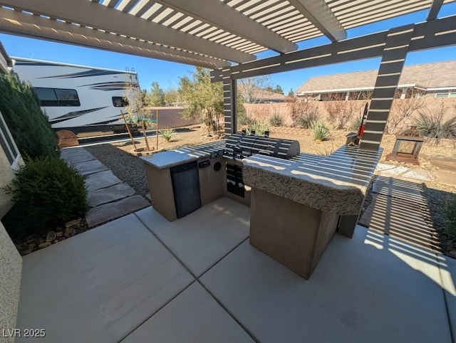 view of patio featuring fence, a pergola, and exterior kitchen