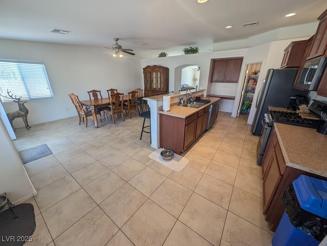 kitchen with arched walkways, a breakfast bar area, a sink, visible vents, and appliances with stainless steel finishes