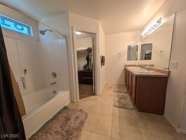 full bathroom featuring double vanity, baseboards, shower / tub combination, a walk in closet, and a sink