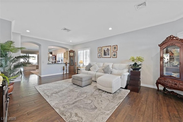 living room with baseboards, visible vents, arched walkways, and dark wood-type flooring