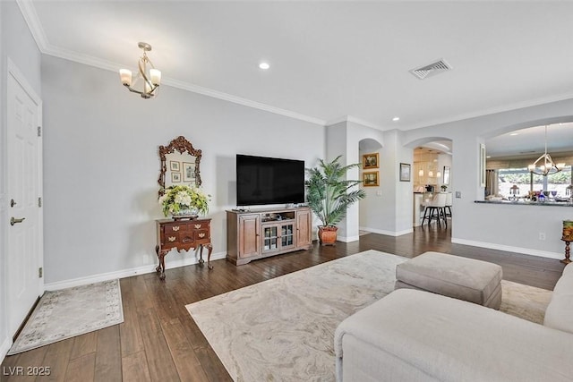 living area with a chandelier, dark wood-style flooring, visible vents, and ornamental molding