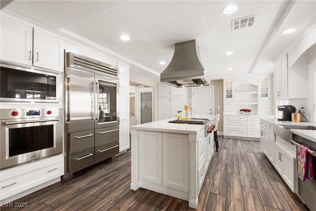 kitchen featuring island range hood, white cabinetry, visible vents, appliances with stainless steel finishes, and dark wood-style floors