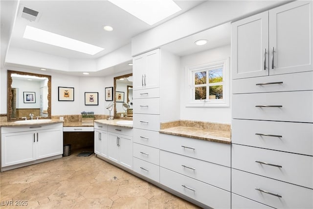 full bathroom with a skylight, two vanities, visible vents, and recessed lighting