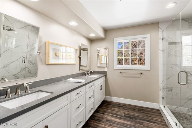 full bathroom with a marble finish shower, a sink, baseboards, and wood finished floors