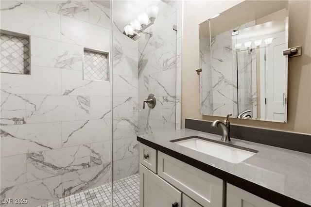 full bath with a marble finish shower and vanity