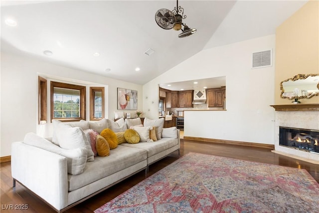 living room featuring dark wood-style floors, a high end fireplace, visible vents, and baseboards