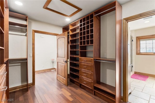 spacious closet featuring dark wood-style floors, visible vents, and attic access