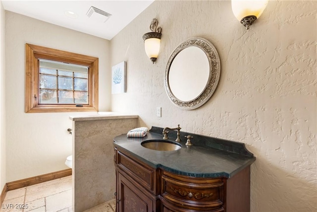 bathroom featuring a textured wall, vanity, visible vents, and baseboards