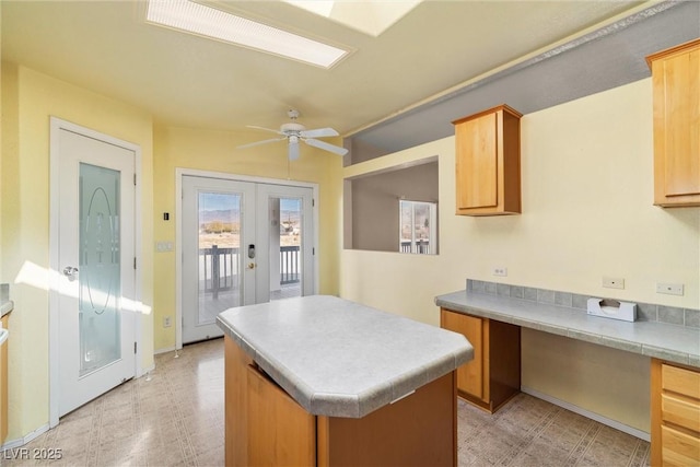 kitchen featuring ceiling fan, french doors, built in study area, a center island, and light floors