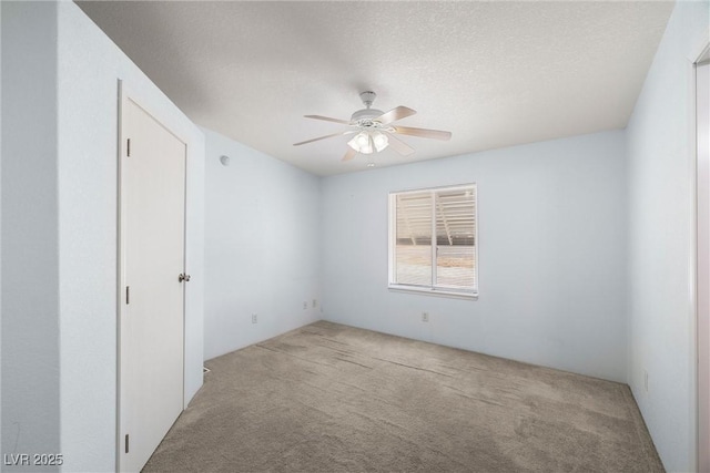 unfurnished room featuring light colored carpet, ceiling fan, and a textured ceiling