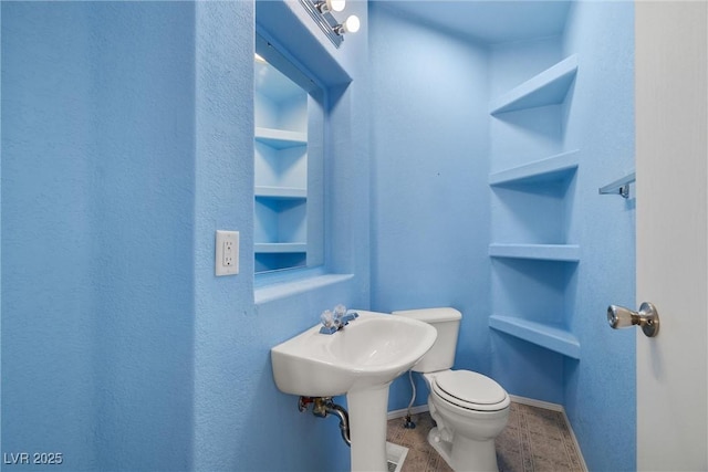 bathroom with built in shelves, toilet, and baseboards