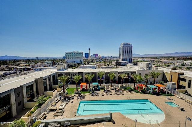 community pool featuring a view of city, a patio, and a mountain view