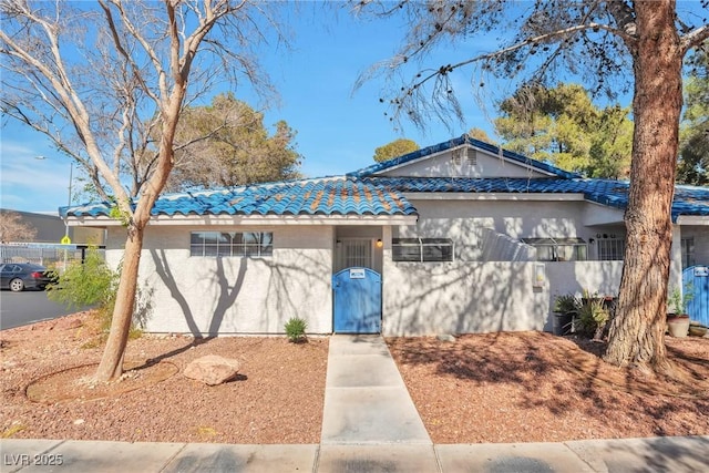 ranch-style house with stucco siding and a tiled roof