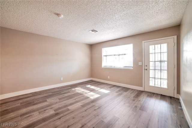 spare room with visible vents, plenty of natural light, and wood finished floors