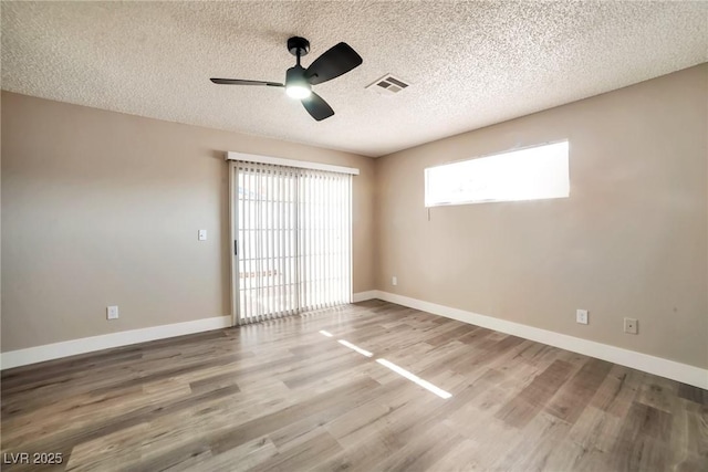 empty room featuring wood finished floors, visible vents, and baseboards