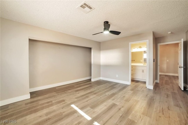 unfurnished bedroom with light wood-type flooring, visible vents, baseboards, and a textured ceiling