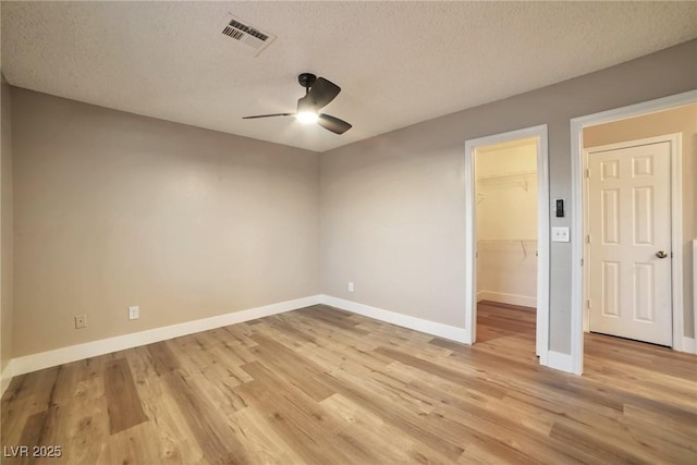 spare room featuring a ceiling fan, light wood-style floors, visible vents, and baseboards