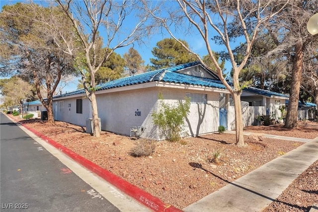 view of side of property featuring stucco siding and a tile roof