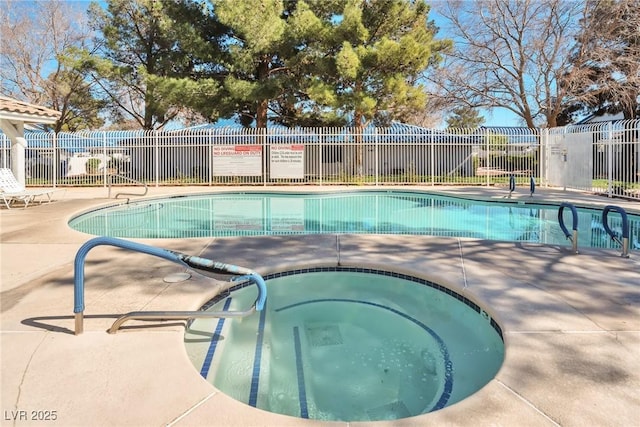 community pool with a patio area, fence, and a hot tub