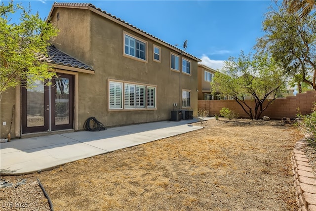 back of property with a tile roof, stucco siding, a patio area, fence, and central AC