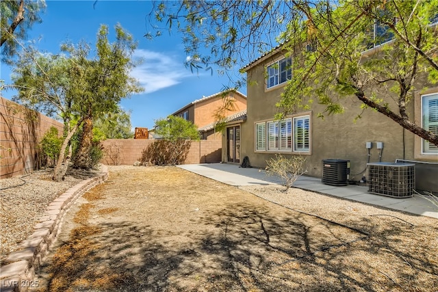 back of property featuring a fenced backyard, a patio, central AC, and stucco siding