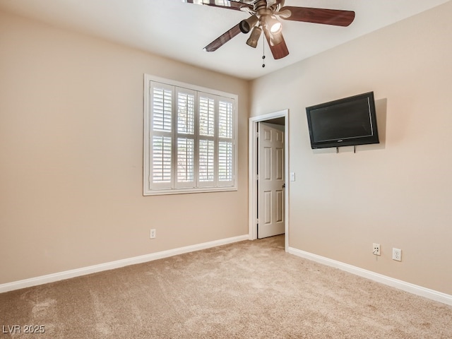 unfurnished room featuring a ceiling fan, light colored carpet, and baseboards