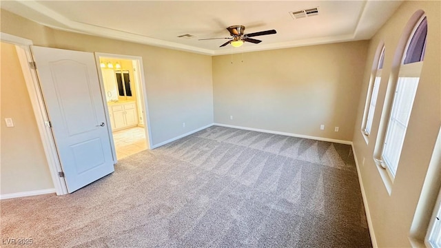 spare room with carpet floors, a ceiling fan, visible vents, and baseboards