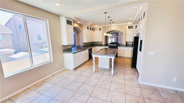 kitchen with baseboards, white cabinetry, a sink, and black appliances