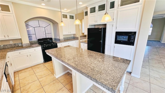 kitchen featuring a kitchen island, light stone countertops, black appliances, white cabinetry, and pendant lighting