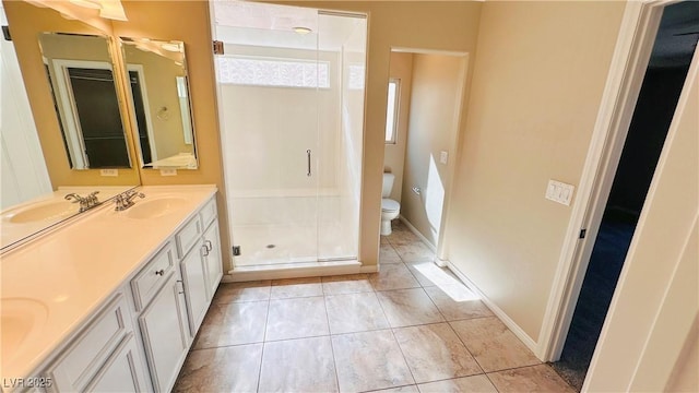 bathroom with a stall shower, a sink, toilet, and double vanity