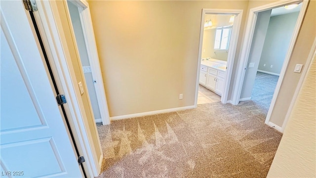 corridor featuring light colored carpet and baseboards