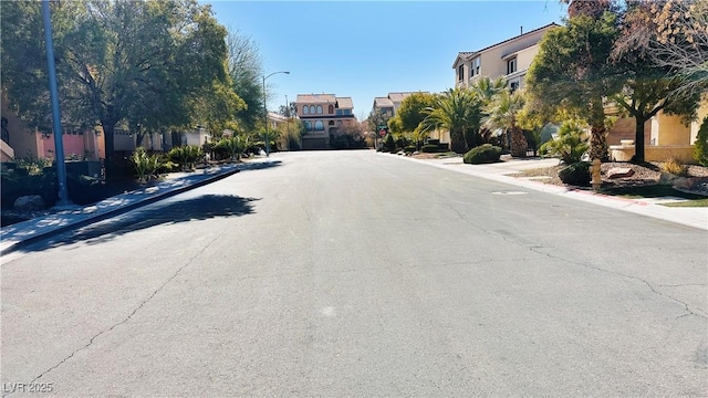 view of road with sidewalks, street lighting, a residential view, and curbs