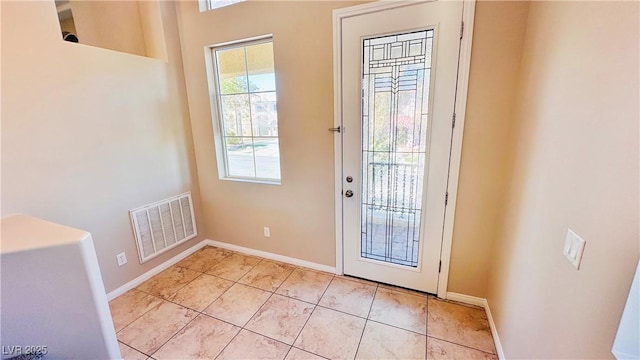 doorway to outside with light tile patterned floors, baseboards, and visible vents