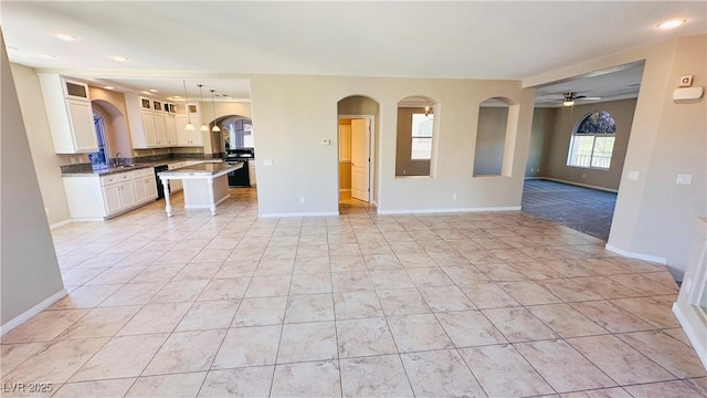 unfurnished living room with light tile patterned floors, recessed lighting, a sink, a ceiling fan, and baseboards