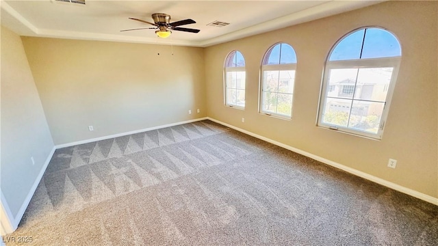 empty room with carpet floors, ceiling fan, baseboards, and a wealth of natural light