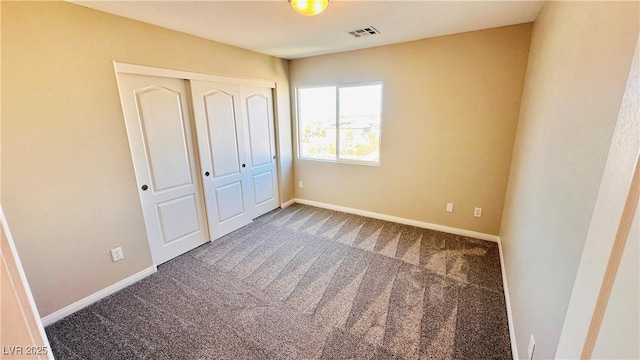 unfurnished bedroom featuring carpet floors, a closet, visible vents, and baseboards