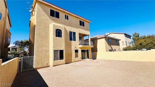 back of house featuring a patio area, a fenced backyard, a balcony, and stucco siding