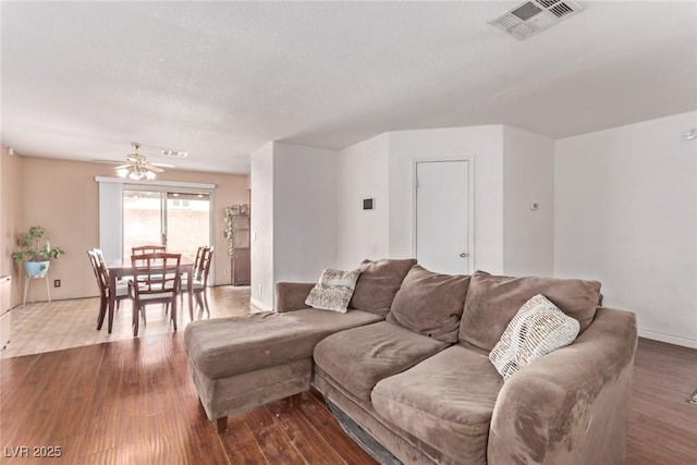 living area with visible vents, ceiling fan, a textured ceiling, and wood finished floors