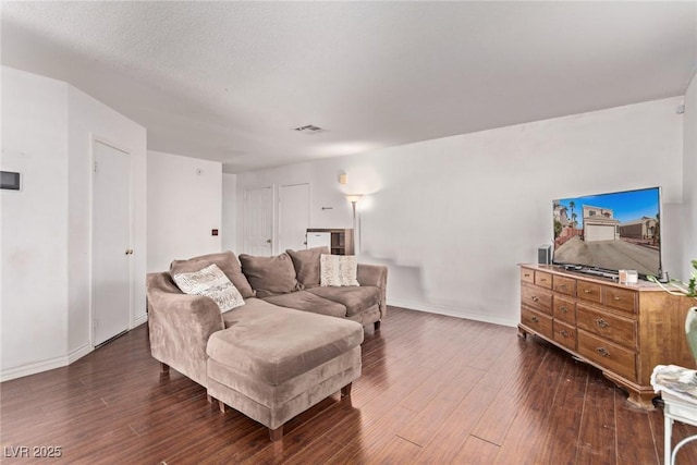 living room with dark wood-style floors, visible vents, and baseboards