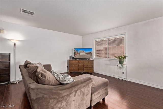 living room featuring visible vents, baseboards, and wood finished floors