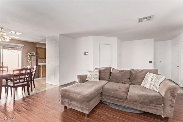 living area featuring ceiling fan, wood finished floors, visible vents, and baseboards