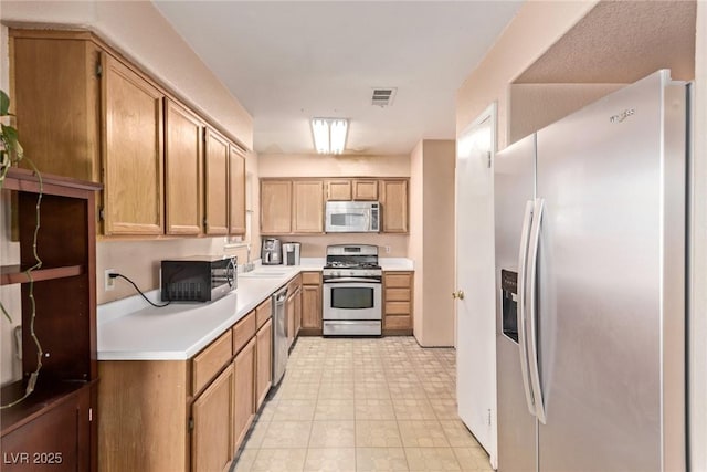 kitchen featuring a sink, stainless steel appliances, light countertops, and visible vents